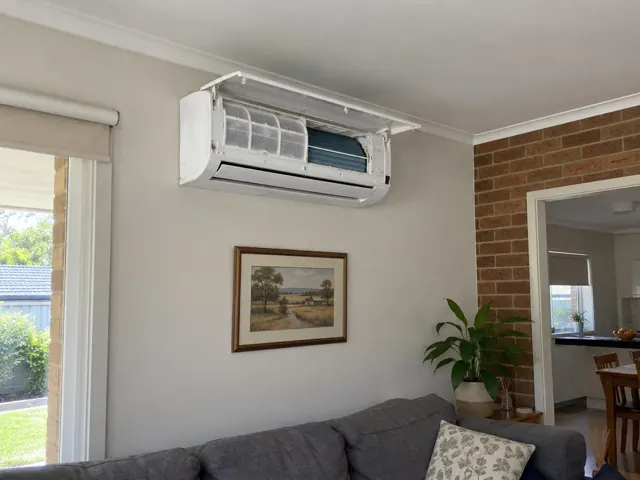 Open split system head with clean filters on a living room wall, above a couch in a home in Woodcroft