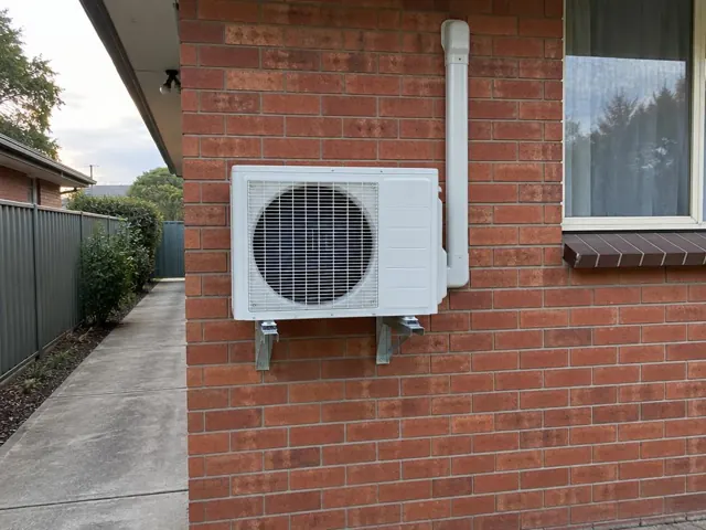 Outdoor split system unit on wall brackets beside a brick house window in Aberfoyle Park